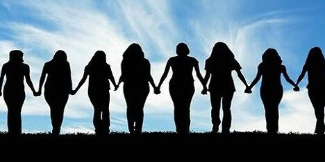 Silhouettes of eleven people standing in a line outdoors, holding hands, with a blue sky and clouds in the background.